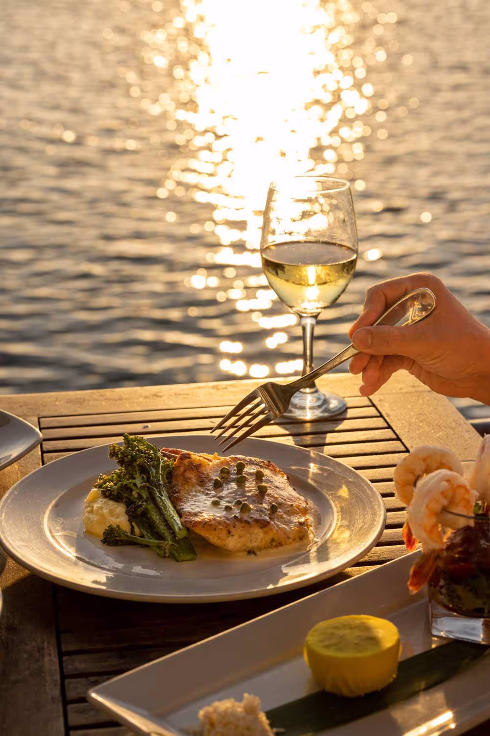 Sunset dinner with white wine on the Boathouse on the Bay patio